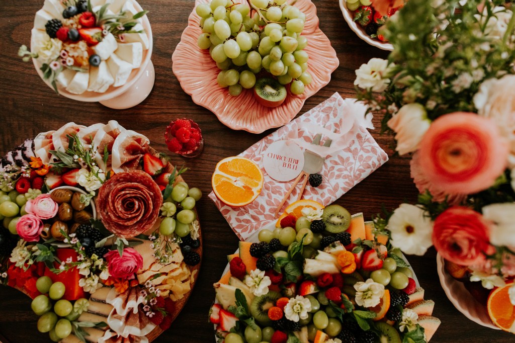 Luxury cheese and charcuterie boards styled with fresh botanicals, artisan cheeses, and seasonal fruit by CharcuterieBrie