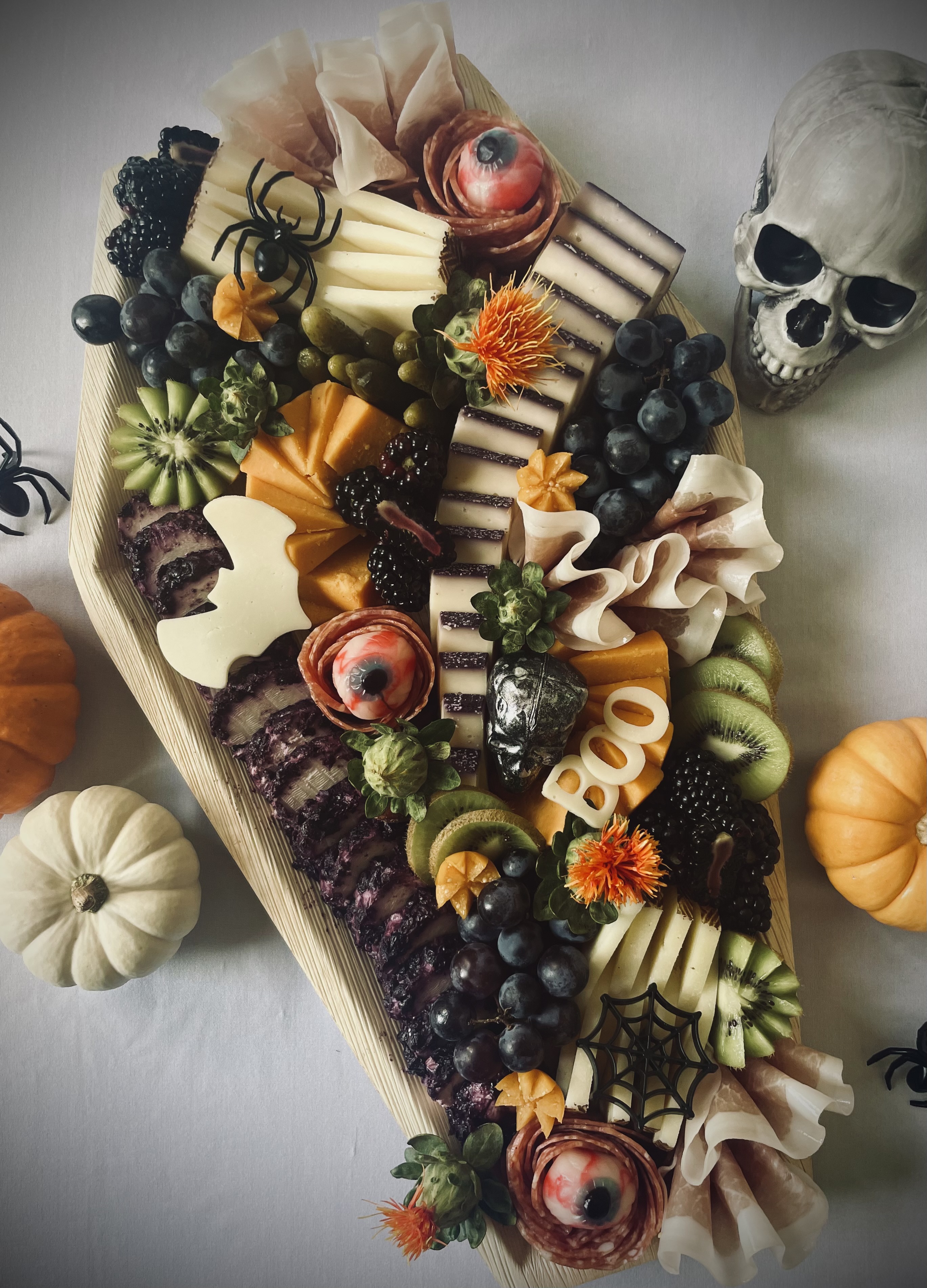 Halloween coffin charcuterie board with artisan cheeses, cured meats, fresh fruit and spooky seasonal details