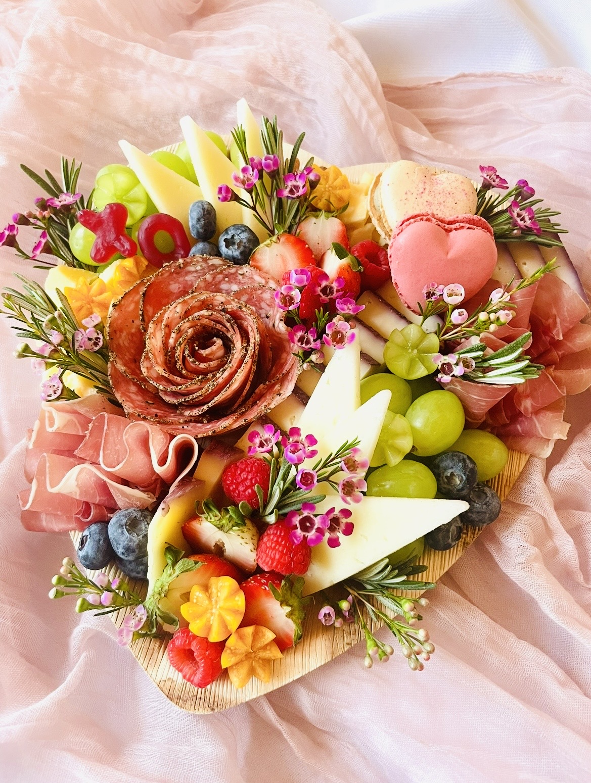 Heart-shaped Valentine’s Day charcuterie board with artisanal cheeses, charcuterie, fresh fruit, and floral accents, handcrafted in the Chicago suburbs.