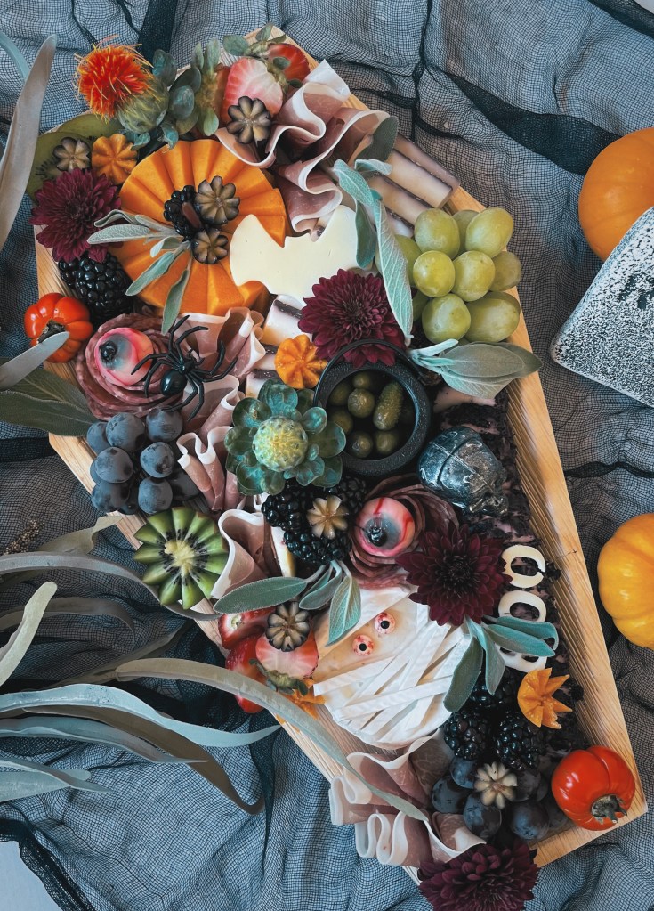 Hauntingly elegant coffin-shaped charcuterie board with artisan cheeses, meats, and florals, available in Chicago, La Grange, and Hinsdale.  Also available in kid-friendly charcuterie versions and Halloween candy board