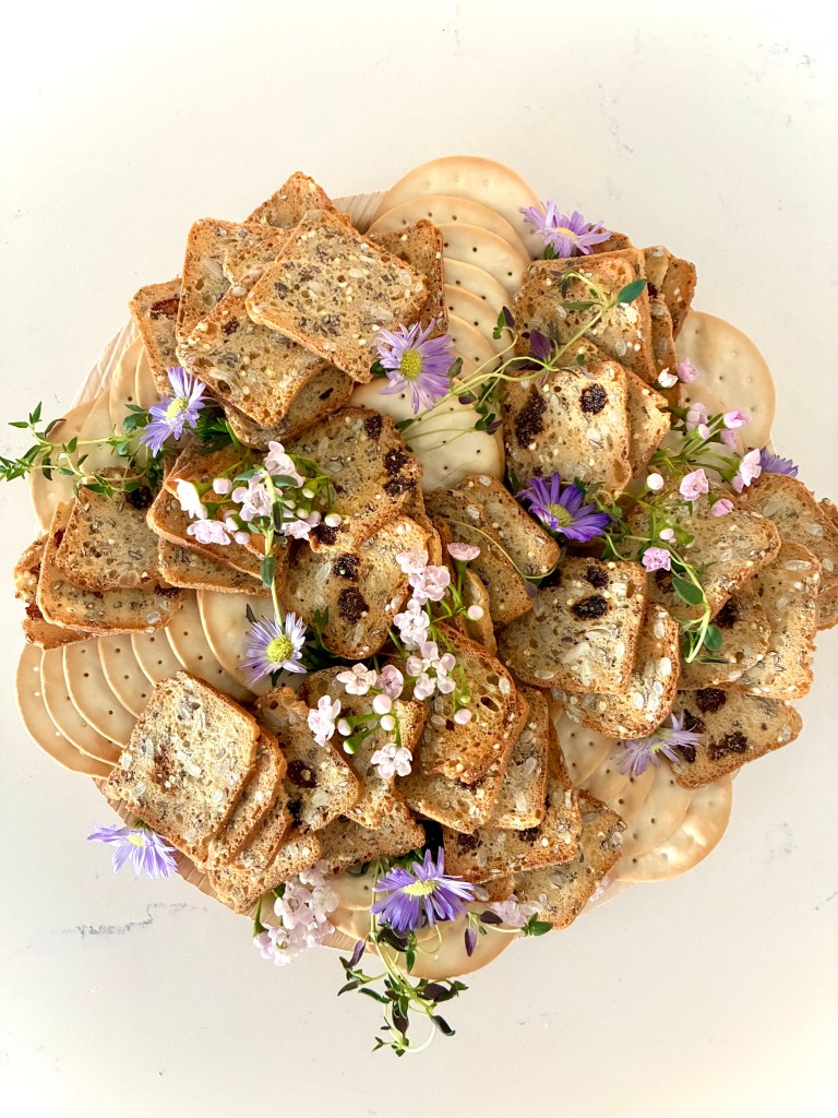 Artfully arranged cracker board featuring assorted artisanal crackers and botanical garnishes — CharcuterieBrie, Chicago luxury charcuterie catering.